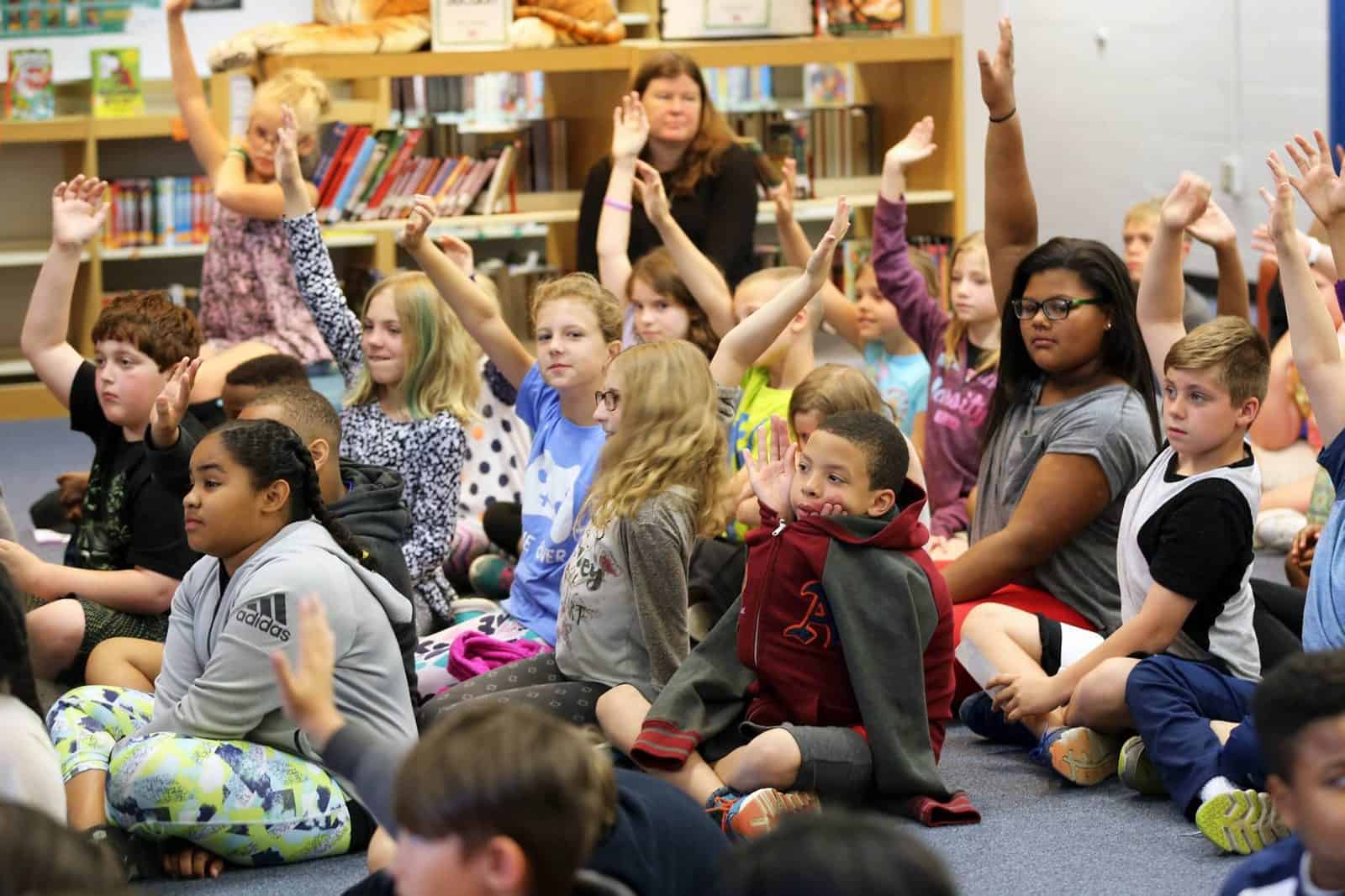 Students raising their hands during a library author visit